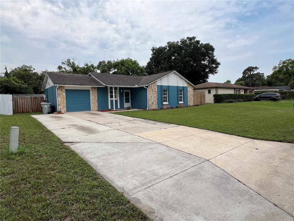 A blue single-story house with a stone facade, a garage, and a concrete driveway — 6 E THRUSH STREET, APOPKA, FL