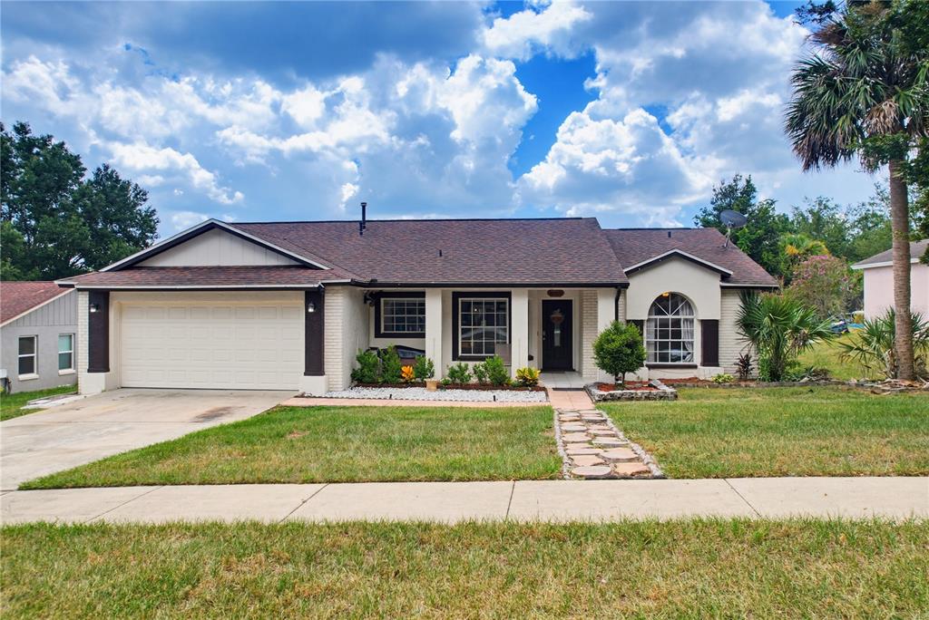 A single-story house with a white brick exterior, dark trim, and a two-car garage — 15904 LAKE ORIENTA COURT, CLERMONT, FL