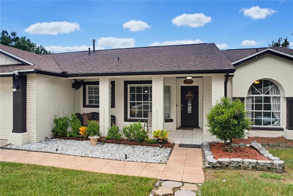 A single-story house with a covered porch, white stucco walls, and a dark shingled roof — 15904 LAKE ORIENTA COURT, CLERMONT, FL
