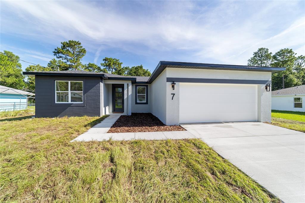 A single-story house with a white stucco facade, a gray accent wall, and a concrete driveway — 7 OAK TRAIL, OCALA, FL
