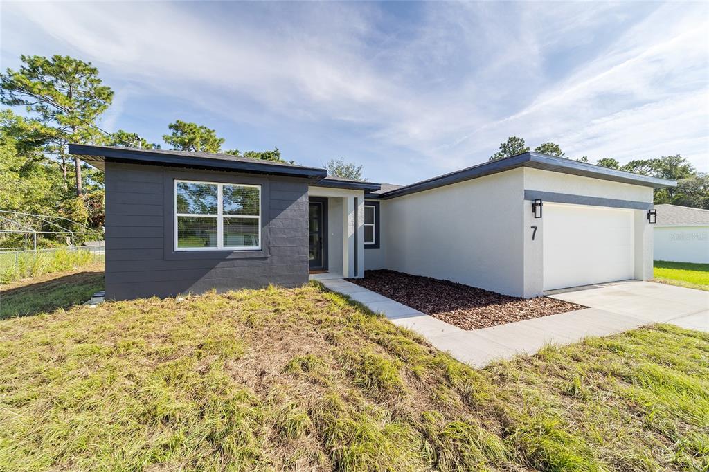 A modern single-story house features a dark gray facade, white stucco, and a two-car garage — 7 OAK TRAIL, OCALA, FL