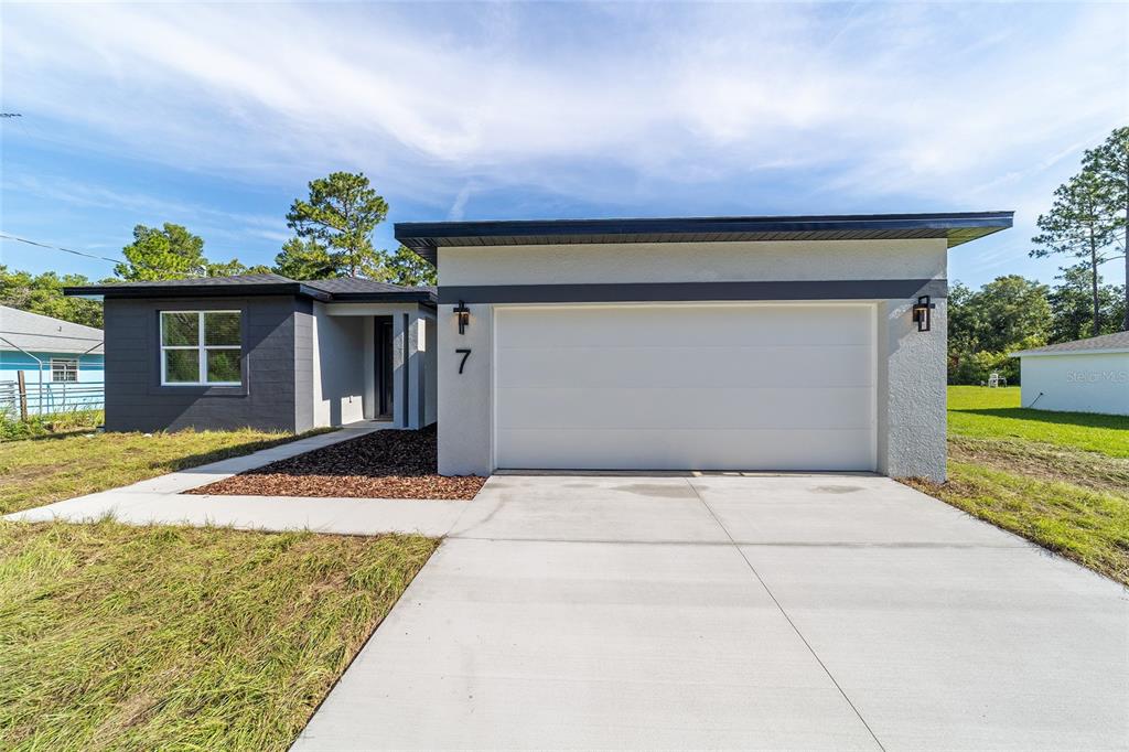 A single-story house with a white garage, gray siding, and a concrete driveway — 7 OAK TRAIL, OCALA, FL