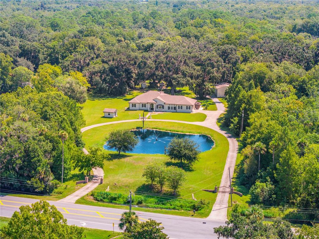 An aerial view shows a single-story house with a circular driveway and pond — 1780 OLD MISSION ROAD, EDGEWATER, FL