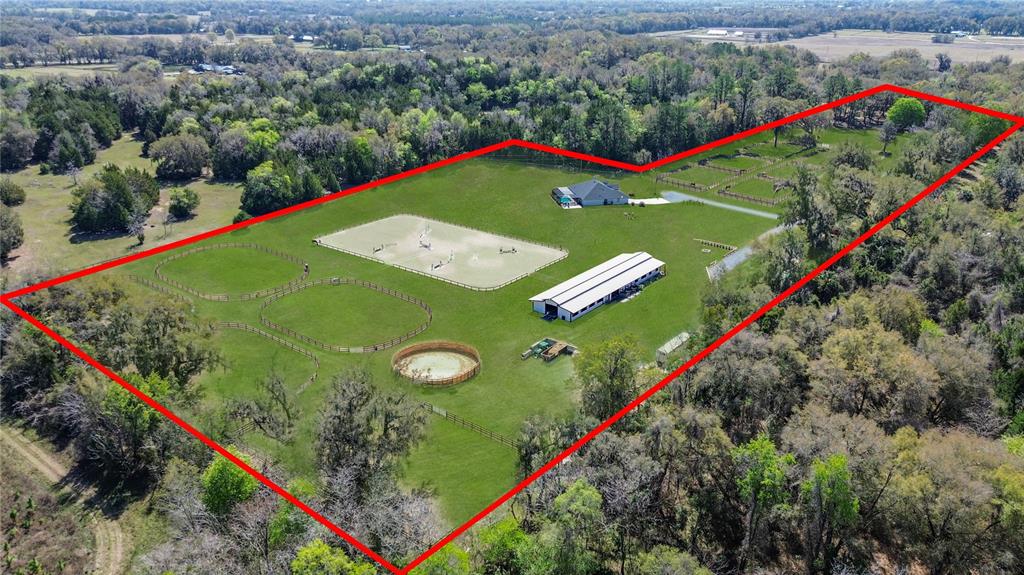An aerial view shows a rural property with a house, barn, and fenced horse pastures — 3245 NW 137TH PLACE, REDDICK, FL