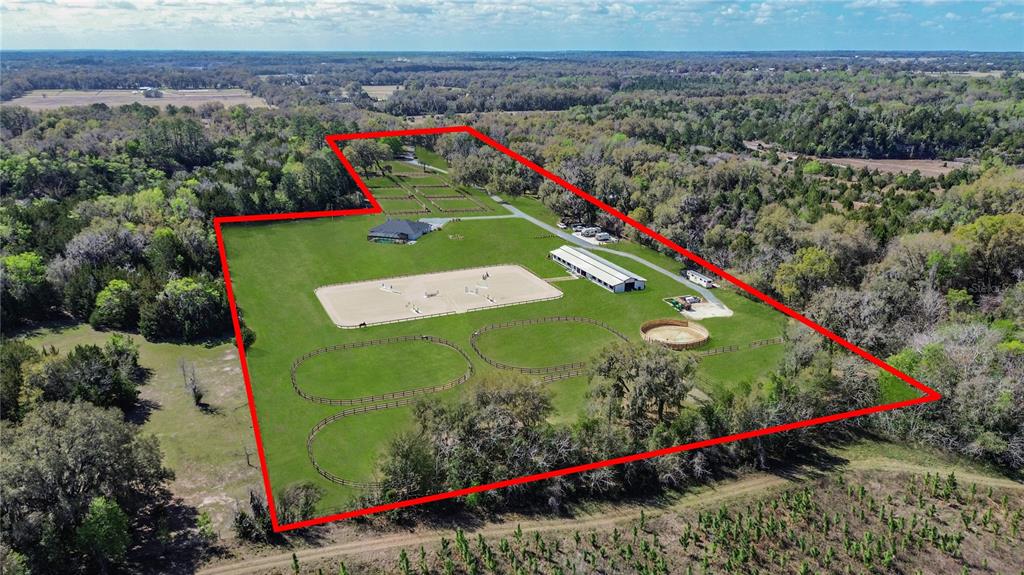 An aerial view shows a rural property with a house, horse stables, and riding arenas — 3245 NW 137TH PLACE, REDDICK, FL
