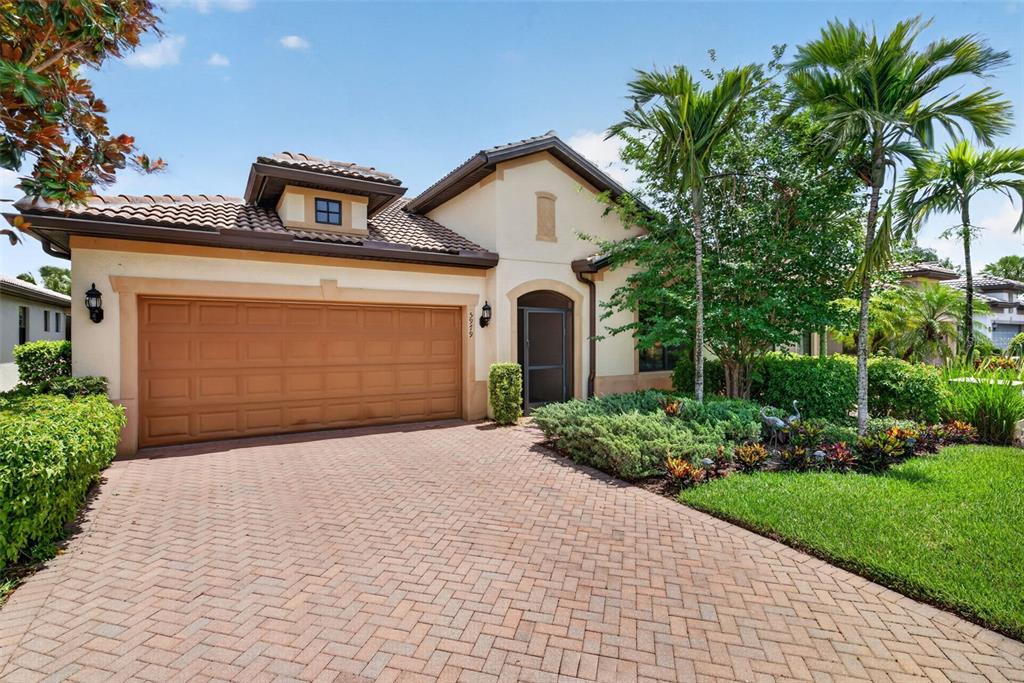 A single-story house with a tan stucco exterior, a brown tile roof, and a paver driveway — 5979 PROSPERITY LANE, IMMOKALEE, FL