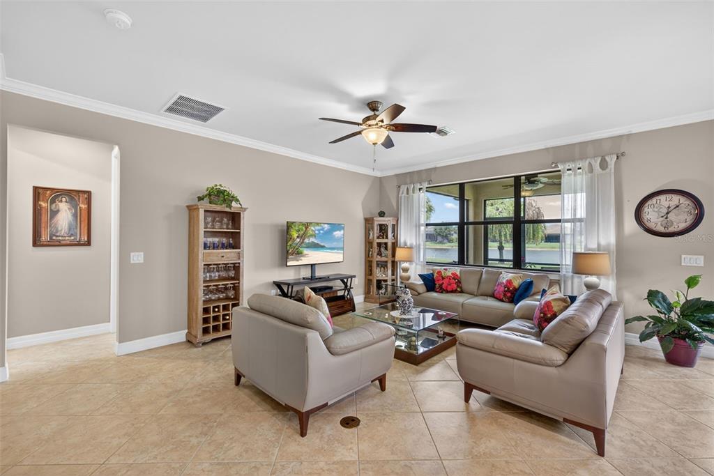 A living room features tile flooring, a ceiling fan, a television, and leather furniture — 5979 PROSPERITY LANE, IMMOKALEE, FL