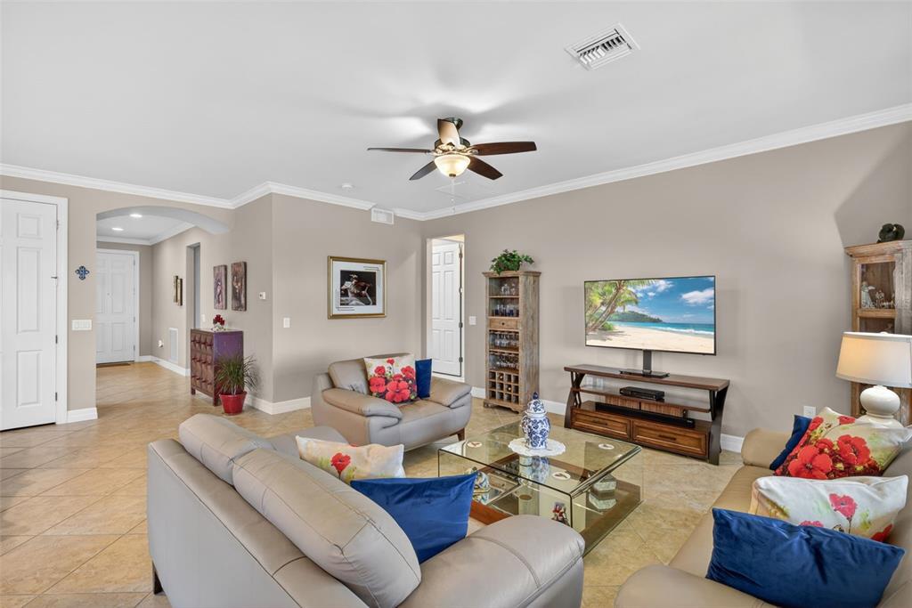 A living room features beige walls, tile flooring, leather furniture, and a television on a stand — 5979 PROSPERITY LANE, IMMOKALEE, FL