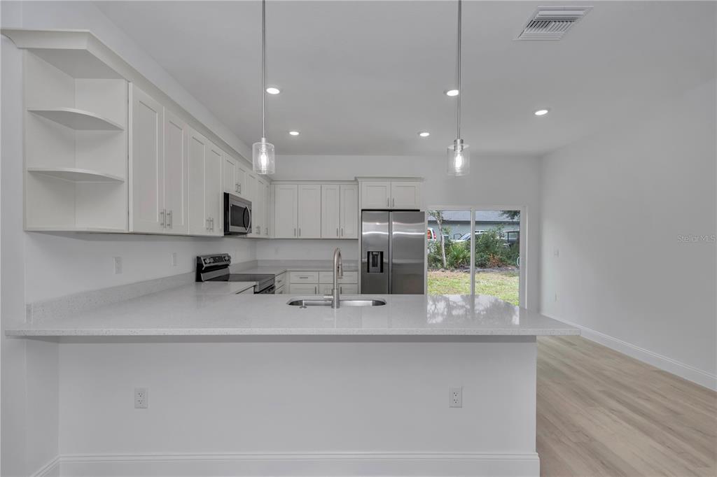 A modern kitchen features white cabinets, quartz countertops, stainless steel appliances, and two pendant lights — 15751 SW 40TH TERRACE, OCALA, FL