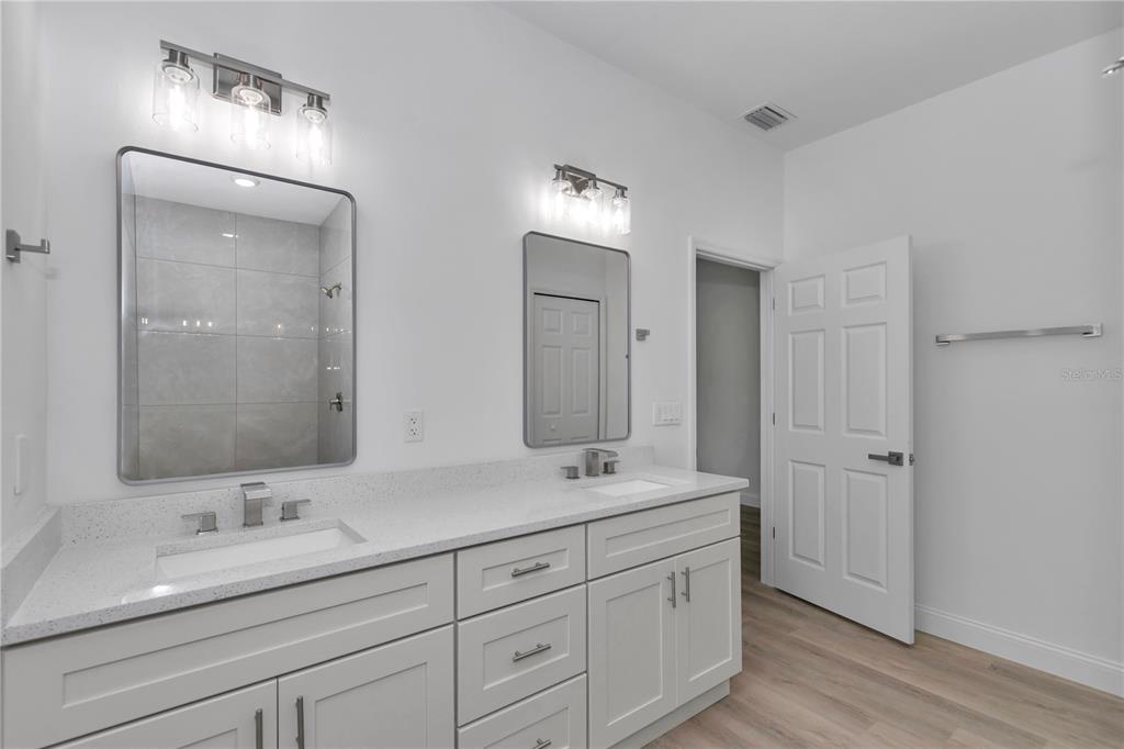 A modern bathroom features a double vanity with white cabinets, quartz countertops, and two mirrors — 15751 SW 40TH TERRACE, OCALA, FL
