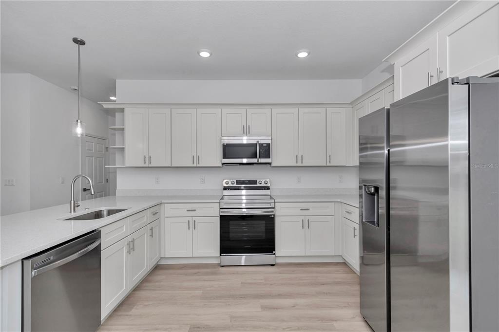 A modern kitchen features white cabinets, stainless steel appliances, and a quartz-topped island — 15751 SW 40TH TERRACE, OCALA, FL