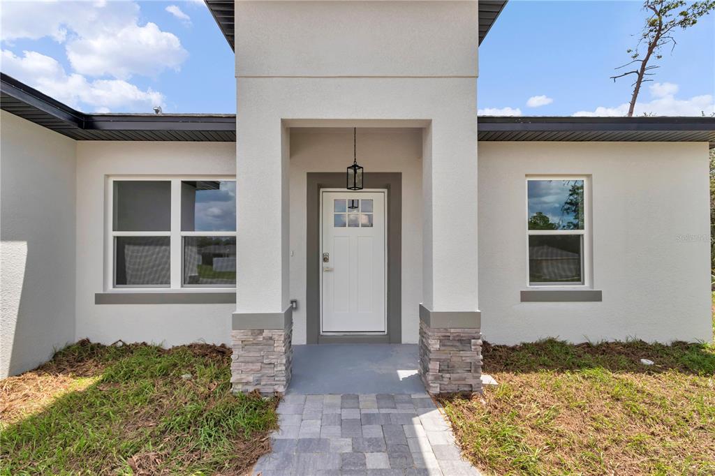 The exterior of a modern house features a white stucco facade, stone accents, and a walkway — 15751 SW 40TH TERRACE, OCALA, FL