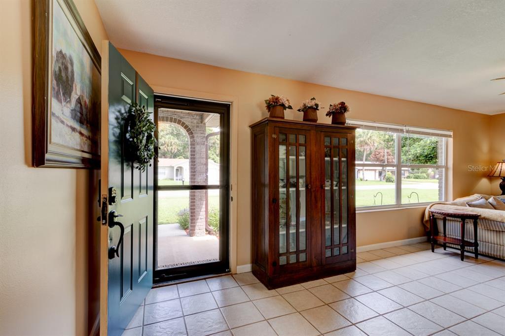An entryway with tiled floors, a dark wood cabinet, and a door opening to a porch — 16 LAUREL OAKS CIRCLE, ORMOND BEACH, FL