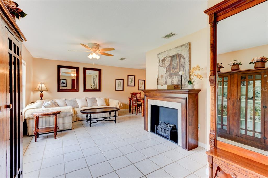 A living room with a fireplace, tile flooring, a beige sectional sofa, and wooden furniture — 16 LAUREL OAKS CIRCLE, ORMOND BEACH, FL