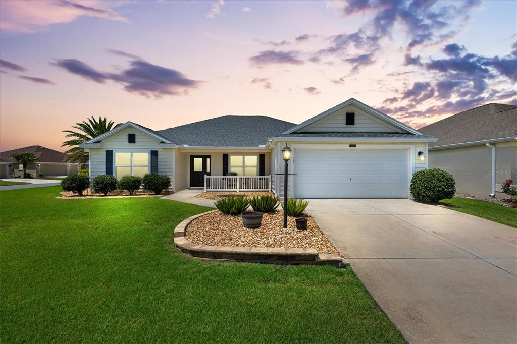 A single-story house with a white garage, a front porch, and a landscaped rock garden — 3602 PEPPERIDGE CIRCLE, THE VILLAGES, FL