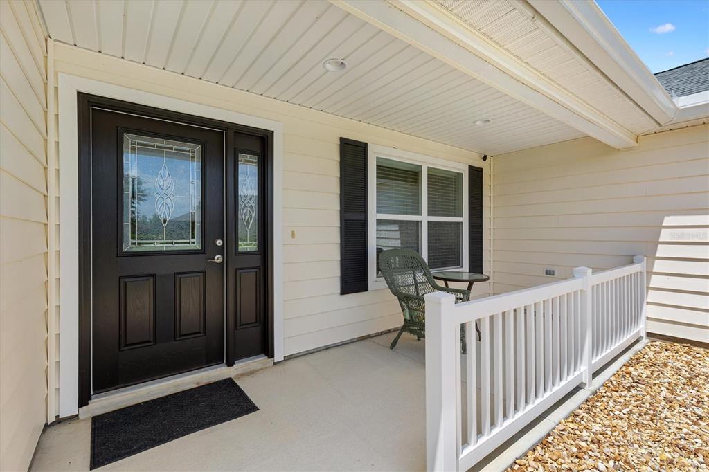 A covered front porch features a dark door with glass panels and a white railing — 3602 PEPPERIDGE CIRCLE, THE VILLAGES, FL