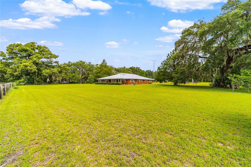 A single-story brick house sits in the middle of a large, grassy field — 2285 W HIGHWAY 318, CITRA, FL