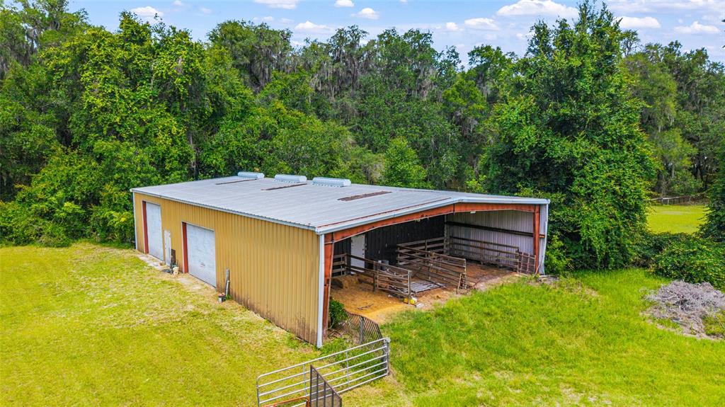 An aerial view of a metal barn with an open-sided stall area in a field — 2285 W HIGHWAY 318, CITRA, FL