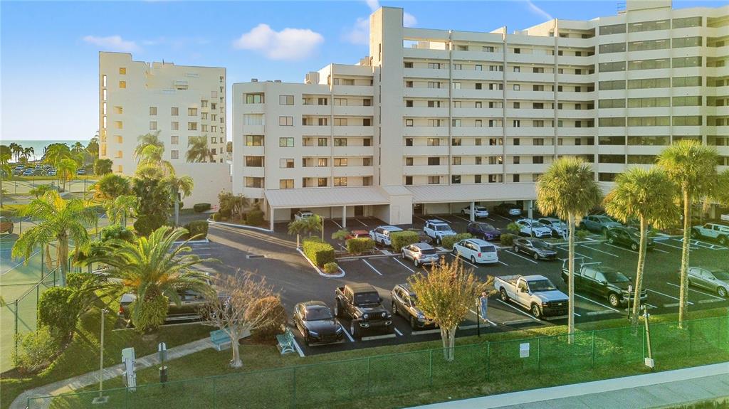 An exterior view of a multi-story apartment building with a parking lot and palm trees — 6035 SEA RANCH DRIVE UNIT 203, HUDSON, FL
