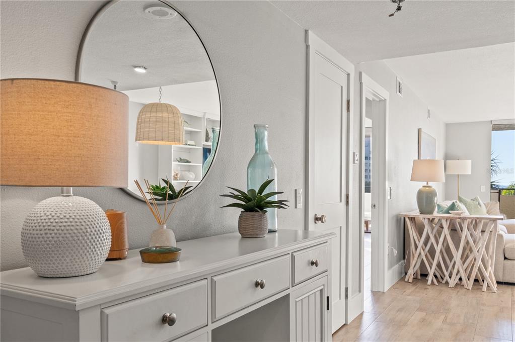 A white console table sits beneath a round mirror in a bright, coastal-style entryway — 6035 SEA RANCH DRIVE UNIT 203, HUDSON, FL