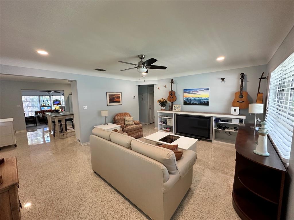 A living room features light-colored tile floors, a beige sofa, and guitars mounted on the wall — 2831 CLINTON STREET S, GULFPORT, FL