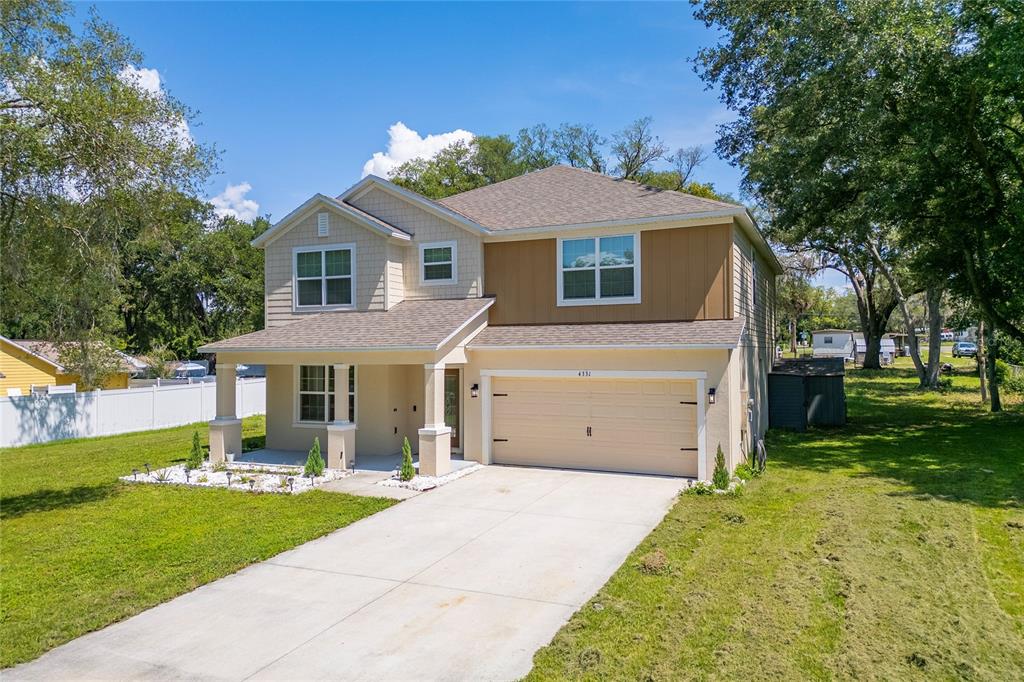 A two-story suburban house with a beige exterior, a two-car garage, and a front porch — 4331 WAYNE ROAD, FRUITLAND PARK, FL