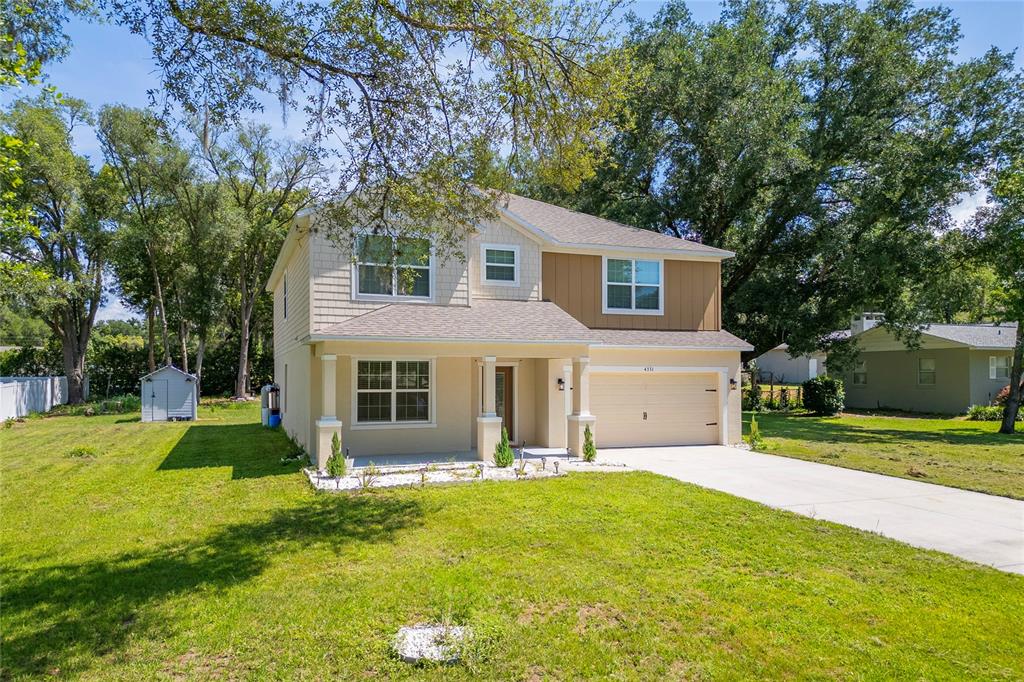 A two-story suburban house with a tan exterior, a front porch, and a two-car garage — 4331 WAYNE ROAD, FRUITLAND PARK, FL