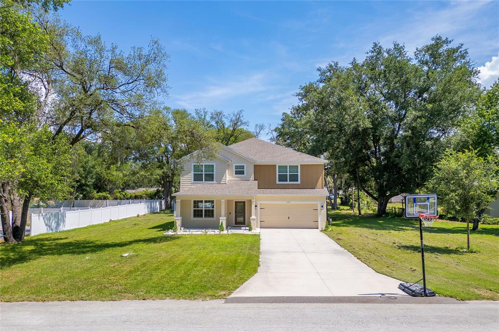 A two-story house with a tan exterior, a two-car garage, and a basketball hoop outside — 4331 WAYNE ROAD, FRUITLAND PARK, FL