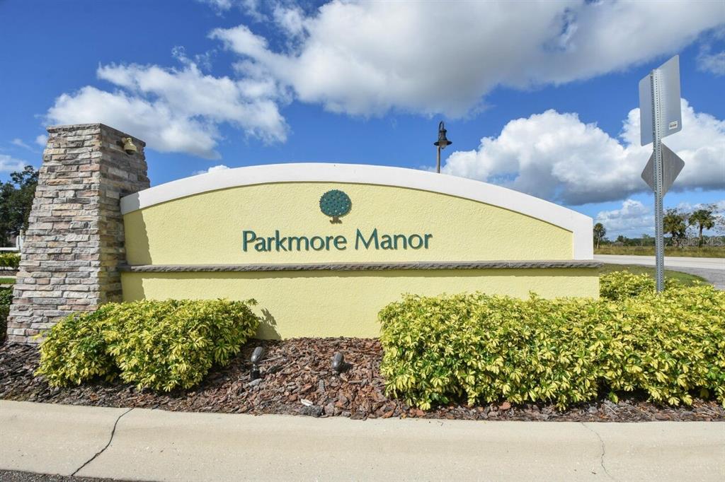 A stone-accented monument sign for Parkmore Manor sits behind a landscaped garden bed — 831 OAK HOLLOW LOOP, DELAND, FL