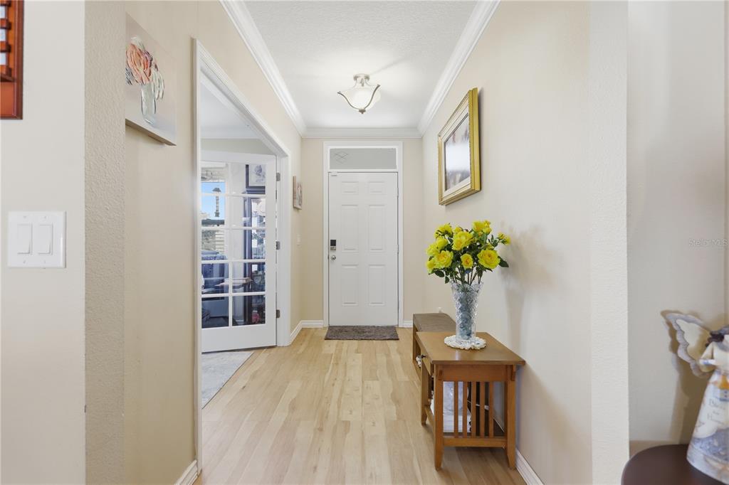 A bright entryway features light wood flooring, a white front door, and a small table — 831 OAK HOLLOW LOOP, DELAND, FL