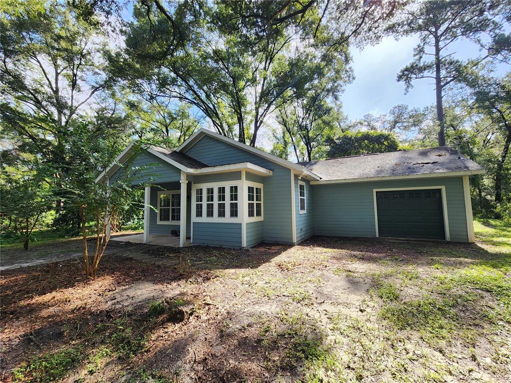 A blue single-story house with a front porch, bay window, and attached garage — 8909 SE 2ND STREET ROAD, TRENTON, FL