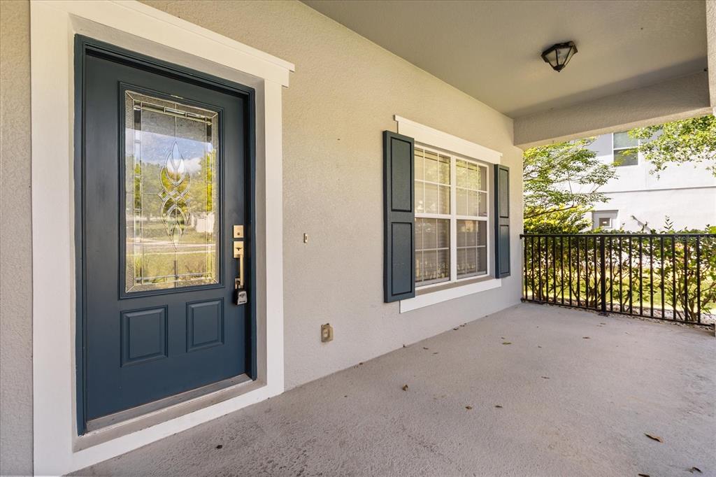 A covered front porch features a blue front door, a window with shutters, and railings — 20934 SULLIVAN RANCH BOULEVARD, MOUNT DORA, FL