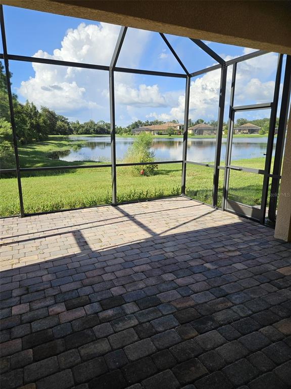 A screened-in patio with brick pavers overlooks a lake and grassy backyard — 12324 CANAVESE LANE, VENICE, FL
