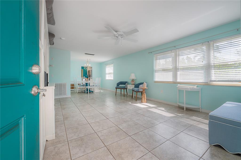 An open-concept dining and living area features light blue walls, tile flooring, and white blinds — 2960 59TH STREET S UNIT 101, GULFPORT, FL