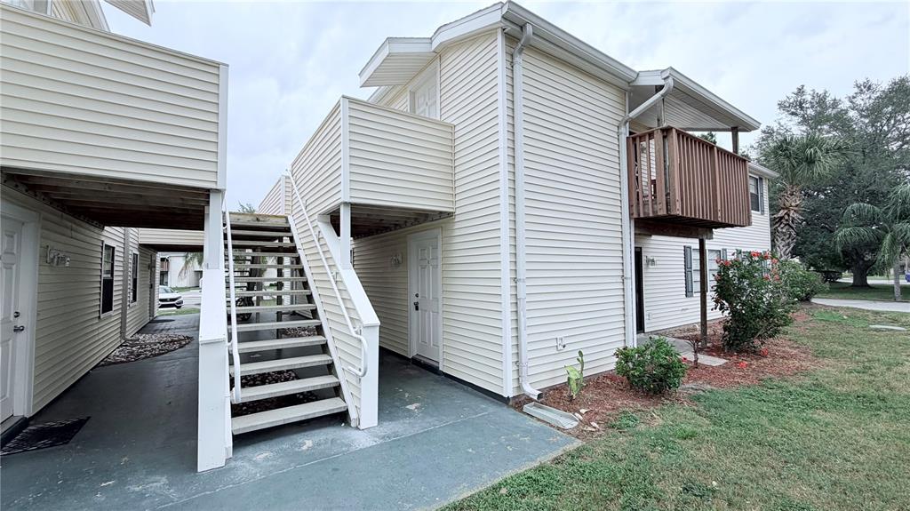 An exterior view of a two-story apartment building with beige siding and an outdoor staircase — 131 SABAL COURT UNIT E, OLDSMAR, FL