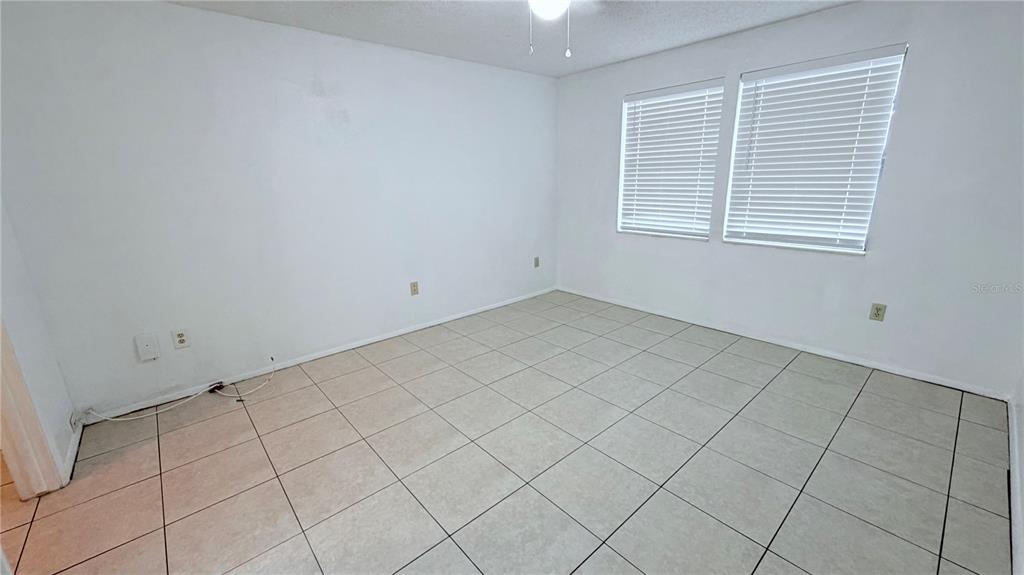 An empty room with white walls, tile flooring, and two windows with white blinds — 131 SABAL COURT UNIT E, OLDSMAR, FL