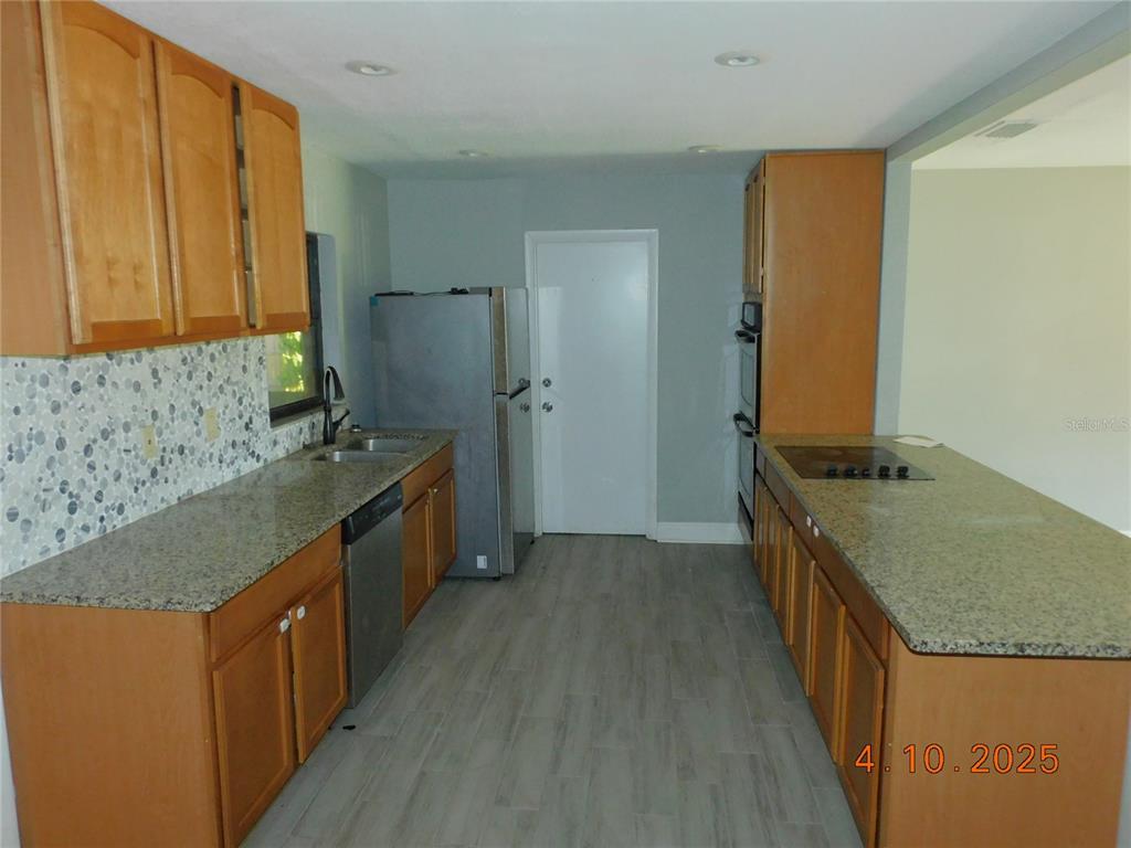 A kitchen features wood cabinets, granite countertops, stainless steel appliances, and a tiled backsplash — 436 MICHIGAN AVENUE, ST CLOUD, FL
