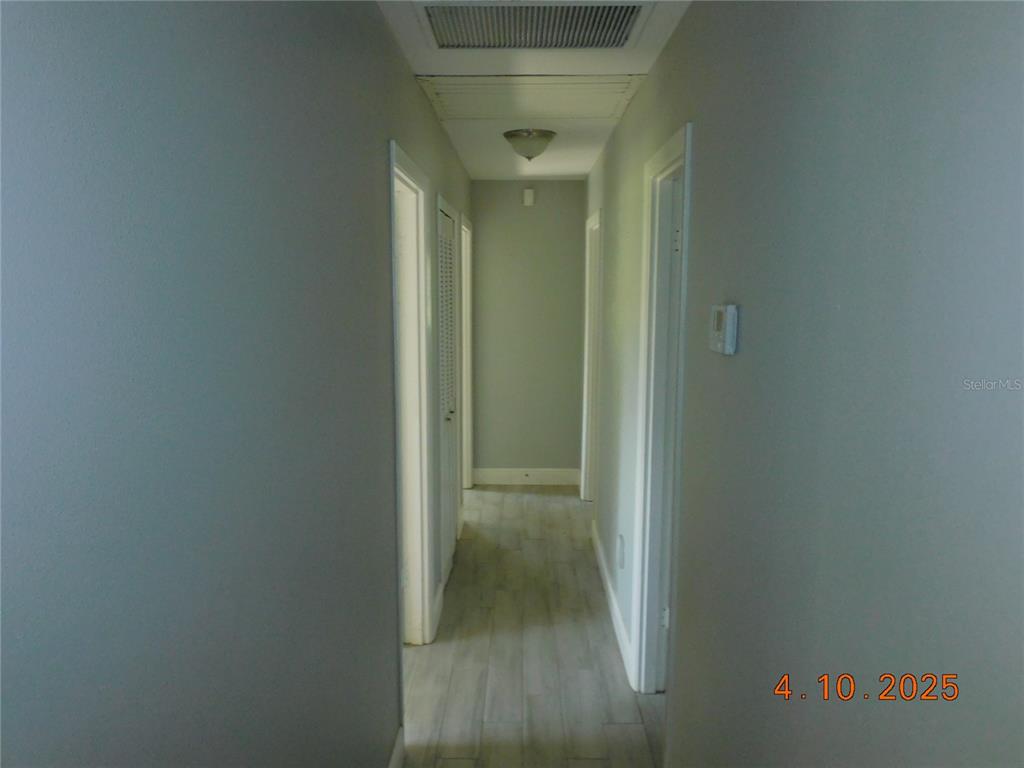 A narrow hallway features light gray walls, white trim, and wood-look flooring — 436 MICHIGAN AVENUE, ST CLOUD, FL