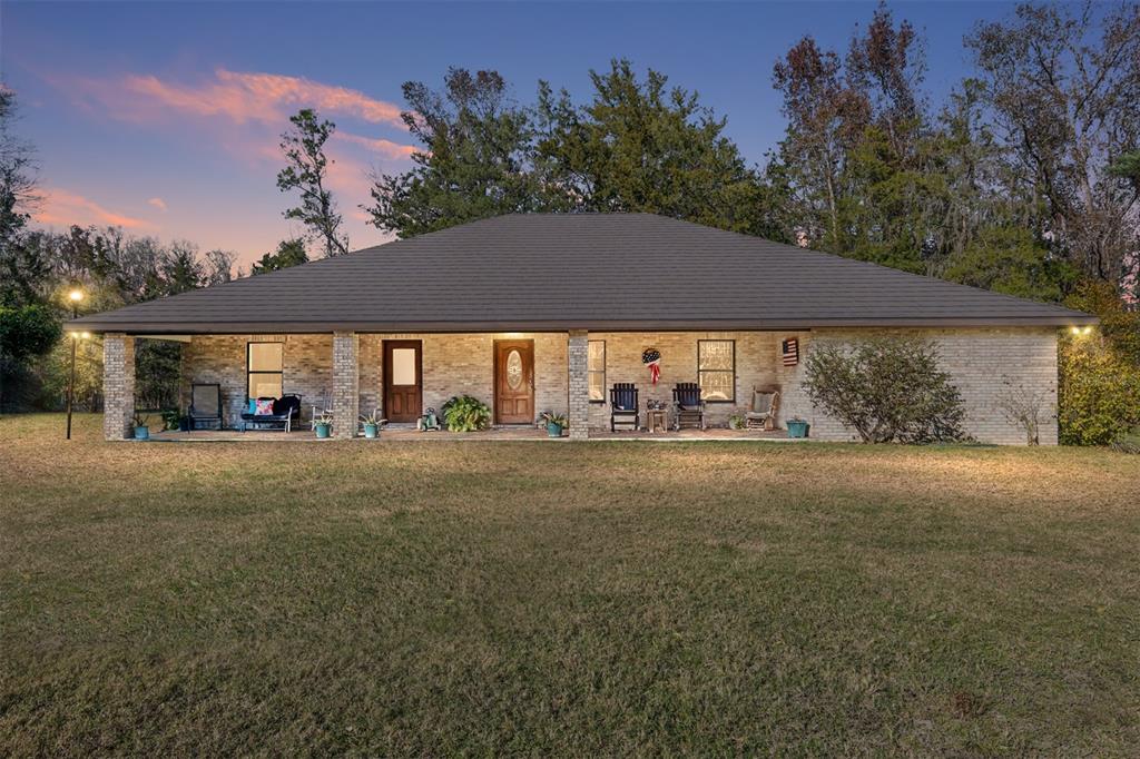 A single-story brick house with a covered front porch sits on a grassy lawn at dusk — 2821 SE 80TH STREET, OCALA, FL