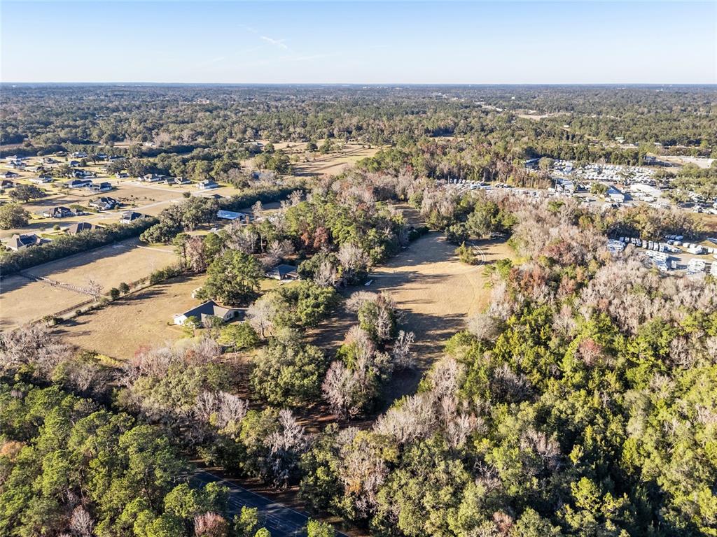 An aerial view shows a rural landscape with scattered houses, open fields, and dense woods — 2821 SE 80TH STREET, OCALA, FL