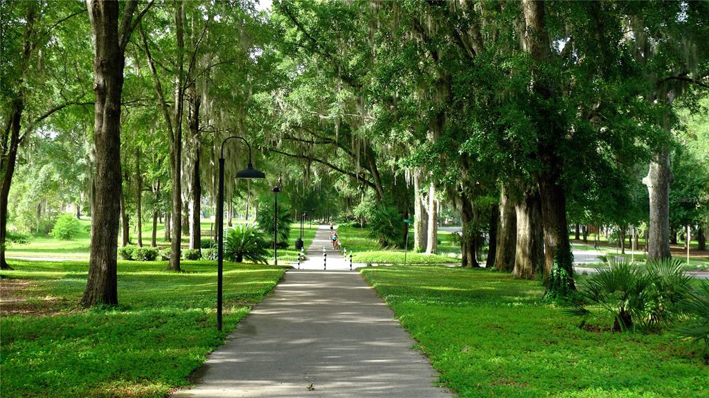 A paved walking path winds through a lush, tree-lined park with hanging Spanish moss — 13363 SW 9TH ROAD, NEWBERRY, FL