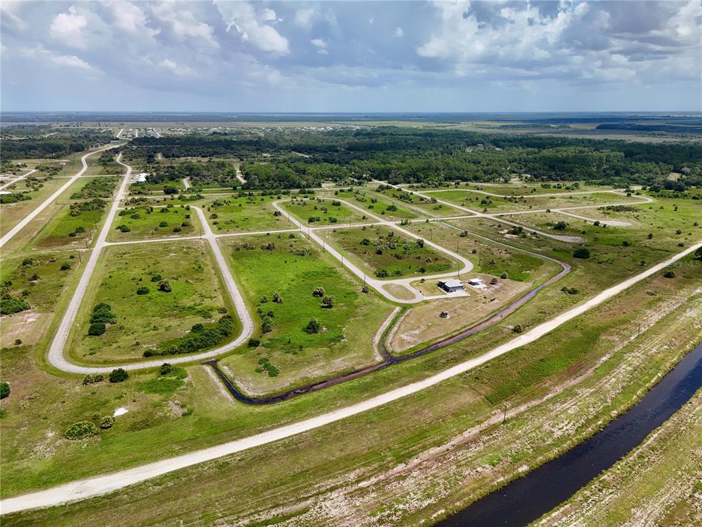 An aerial view shows a rural subdivision with paved roads, vacant lots, and one small building — 216 LYNBROOK LOOP, LABELLE, FL