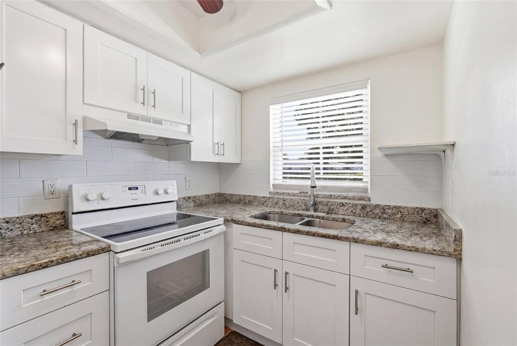 A kitchen features white cabinets, granite countertops, a white electric range, and a window — 404 E ORLANDO AVENUE UNIT 11B, OCOEE, FL