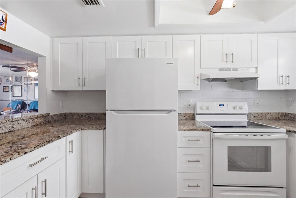A kitchen features white cabinetry, granite countertops, a white refrigerator, and a white electric range — 404 E ORLANDO AVENUE UNIT 11B, OCOEE, FL