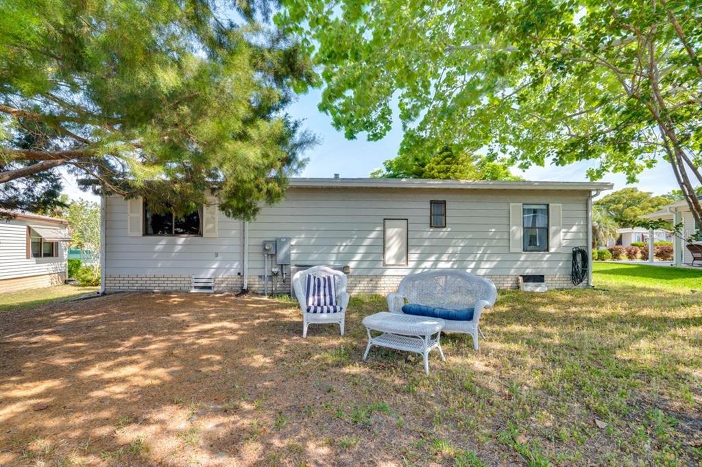 A light gray house exterior with white wicker patio furniture sitting on a grassy lawn — 1224 DUSTIN DRIVE, LADY LAKE, FL