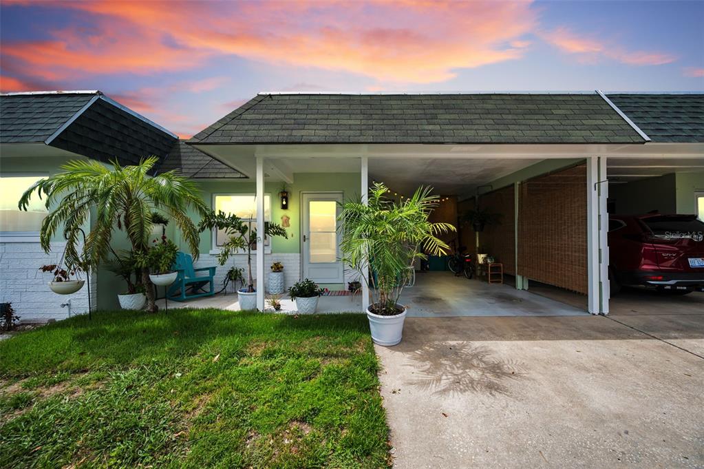 A single-story house exterior features a green facade, a covered carport, and a front lawn — 845 SKY LOCH DRIVE S, DUNEDIN, FL