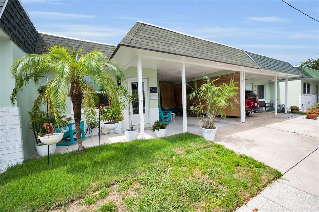 A single-story home with a green shingled roof, a carport, and a small front yard — 845 SKY LOCH DRIVE S, DUNEDIN, FL