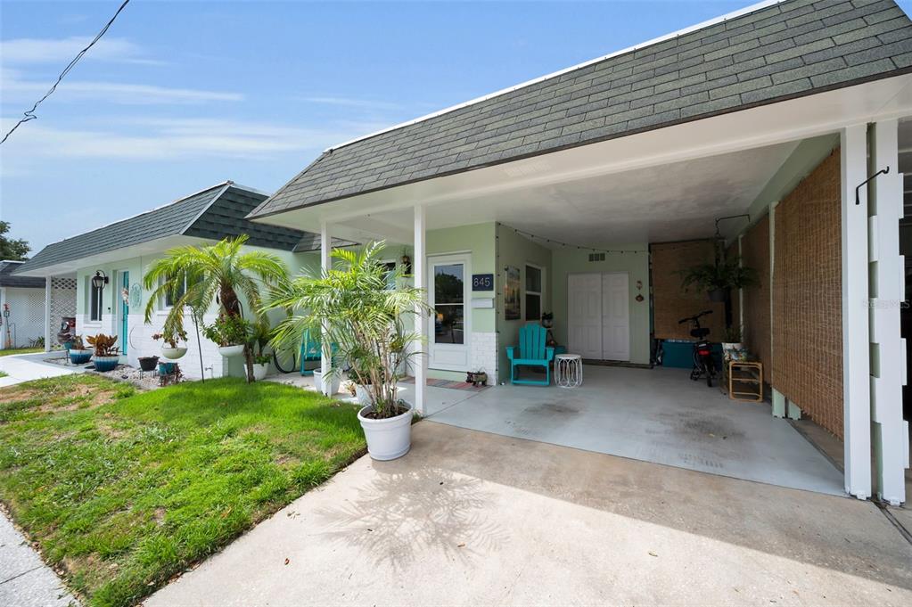 A light green house with a carport, a front lawn, and a paved driveway — 845 SKY LOCH DRIVE S, DUNEDIN, FL