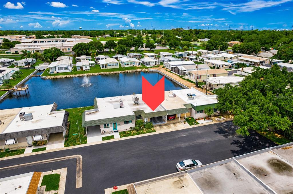 An aerial view shows a row of single-story houses situated along a small lake — 845 SKY LOCH DRIVE S, DUNEDIN, FL