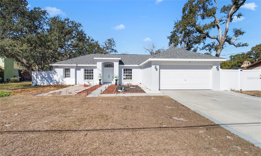 A single-story white house with a gray roof and a two-car garage — 1007 TRYON CIRCLE, SPRING HILL, FL